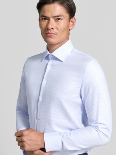 Männermodel trägt Slim Fit Businesshemd aus reiner Baumwolle von Seidensticker in Hellblau mit feiner Struktur, Nahaufnahme Oberkörper, Herren Businesshemd von Seidensticker.