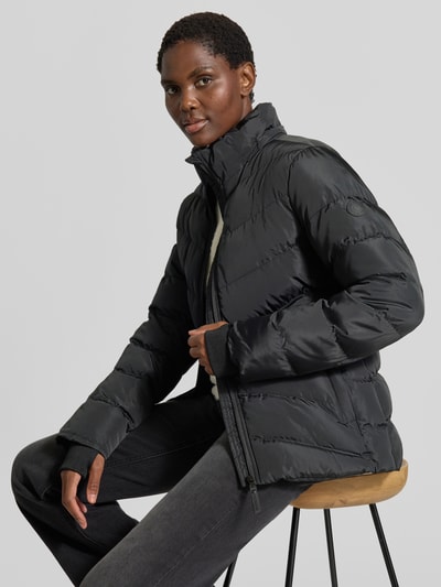 Männermodel trägt Regular Fit Jacke in Stepp-Optik Modell 'Synria' von Cars Jeans, czarna kurtka z efektem pikowania, krój regular fit, kaptur ze stójką, wpuszczane kieszenie, zamek błyskawiczny, długość tyłu w rozmiarze S 65 cm, szerokość ramion w rozmiarze S 42 cm, szerokość w rozmiarze S 50 cm, długość rękawów w rozmiarze S 70 cm, tekstura matowa, cała sylwetka z przodu.