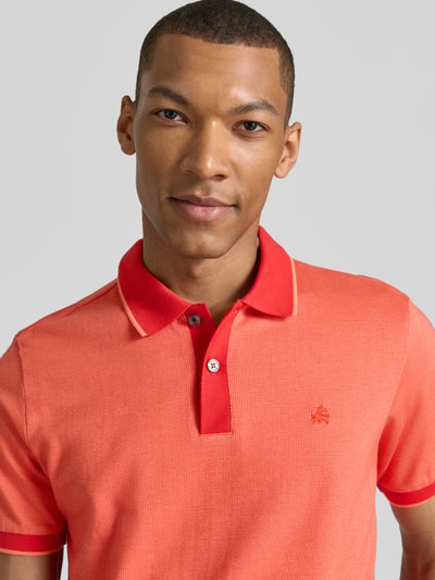 Männermodel trägt Regular Fit Poloshirt mit Logo-Stitching von Lerros in Koralle mit Polokragen und Knopfleiste, Nahaufnahme Oberkörper.