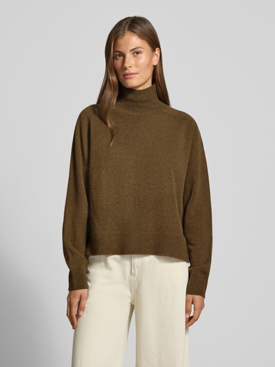 Frauenmodel trägt Strickpullover mit Stehkragen Modell 'LYZIMA' von DRYKORN aus reiner Baumwolle, regular Fit, olivgrün, Ganzkörperansicht von vorne.