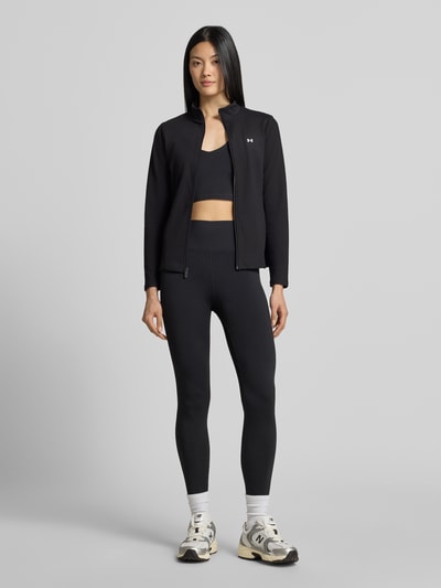 Frauenmodel trägt schwarze Slim Fit Trainingsjacke mit Logo-Print von Under Armour, glatte Struktur, Ganzkörperansicht von vorne, Damen Trainingsjacke von Under Armour.