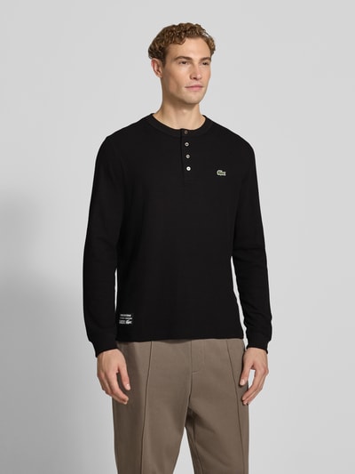 Männermodel trägt Regular Fit Langarmshirt aus reiner Baumwolle von Lacoste in zwart met knopen, Heren Langarmshirt, Ganzkörperansicht von vorne