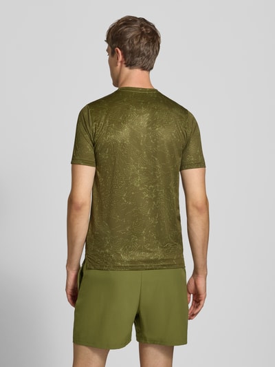 Männermodel trägt T-Shirt mit Logo-Print Modell 'ESSENTIAL' von New Balance in Olivgrün, glatte Textur, dezentes Muster, Ganzkörperansicht Rückansicht. Herren T-Shirt, gerader Schnitt, Rundhalsausschnitt, Rückenlänge bei Größe M 70 cm.