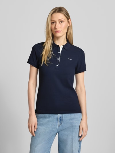 Vrouwenmodel draagt Slim Fit Poloshirt met Label-Stitching van Gant, mix van katoen en elastaan, slim fit, knoopsluiting, ruglengte maat S 59 cm, donkerblauw, Ganzkörperansicht von vorne.