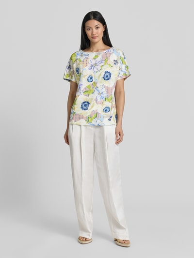 Frauenmodel trägt Damen T-Shirt aus Viskose-Mix mit Stretch-Anteil von Christian Berg Woman im Allover-Look, mit Rundhalsausschnitt, Regular-Fit, florale Muster in Blau, Grün und Gelb auf hellem Grund, glatte Textur, Ganzkörperansicht von vorne.