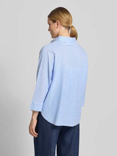 Frauenmodel trägt Relaxed Fit Bluse mit Stitchings und 3/4-Arm von Oui aus reiner Baumwolle, feine blau-weiße Streifen, Rückenlänge 70 cm, Ärmellänge 53 cm, Ganzkörperansicht Rückansicht.