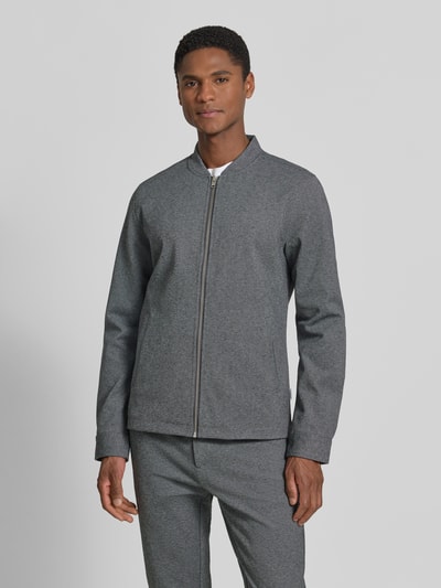 Męski model nosi Regular Fit Sweatjacke mit Stehkragen od Lindbergh w odcieniu szarości, gładka struktura, przód z zamkiem, widok całej sylwetki z przodu.