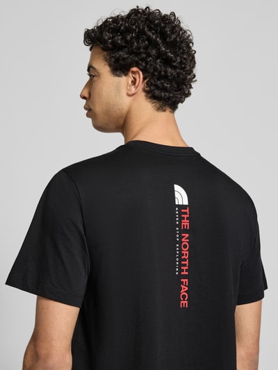 Männermodel trägt Regular Fit T-Shirt aus Baumwoll-Mix Modell 'VERTICAL' von The North Face, Label-Print, schwarze Farbe, Rückenlänge 71 cm, Nahaufnahme Rückansicht.