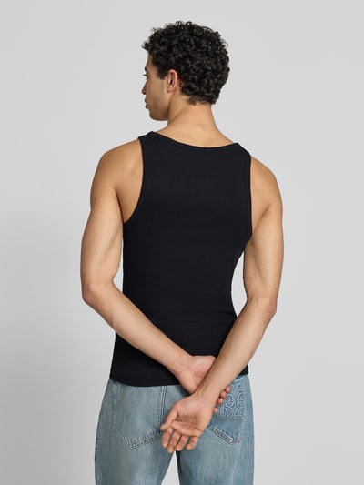 Männermodel trägt Tanktop in Ripp-Optik mit Logo von REVIEW, schwarze Farbe, Slim-Fit aus Reine Baumwolle, Ganzkörperansicht Rückansicht.