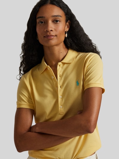 Modelka kobieca ma na sobie Slim Fit Poloshirt aus Baumwoll-Mix od Polo Ralph Lauren, efekt: jednolity kolor, wyhaftowane logo, kołnierzyk polo, listwa guzikowa, krótki rękaw, wykończenie z rozcięciem, pika, mieszanka bawełny; zbliżenie na górną część ciała