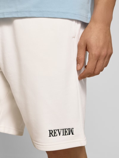 Männermodel trägt Regular Fit Shorts mit Label-Stitching von REVIEW in Weiß, Baumwoll-Mix, Elastischer Bund, Nahaufnahme Oberschenkel.