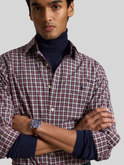 Männermodel trägt Custom Fit Freizeithemd aus reiner Baumwolle von Polo Ralph Lauren, kariertes Muster in Blau, Rot, Beige, Nahaufnahme Oberkörper.