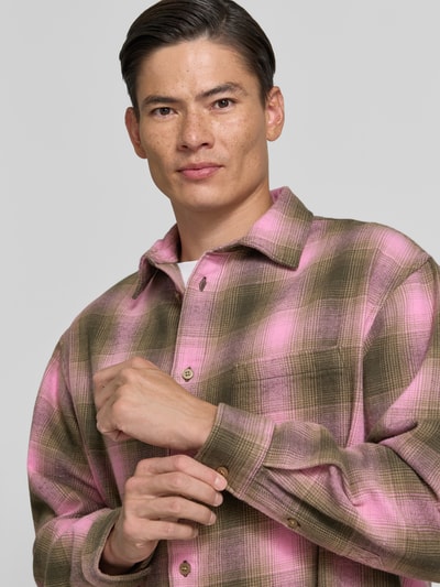 Männermodel trägt Regular Fit Freizeithemd aus Baumwolle Modell 'Carter' von Wood Wood in Rosa und Braun kariert, Nahaufnahme Oberkörper.