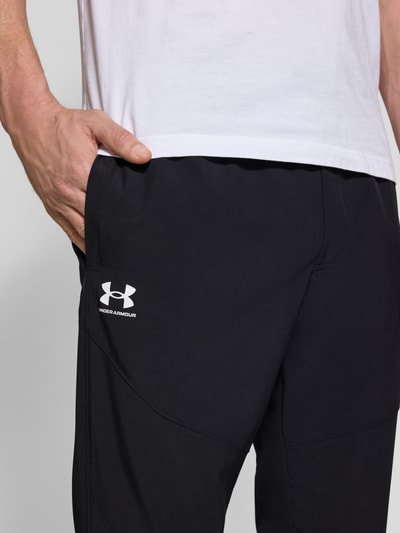 Männermodel trägt Regular Fit Sweatpants mit Logo-Print Modell 'Vibe' von Under Armour, Schwarz, Elastischer-Material-Mix, Nahaufnahme Oberkörper.