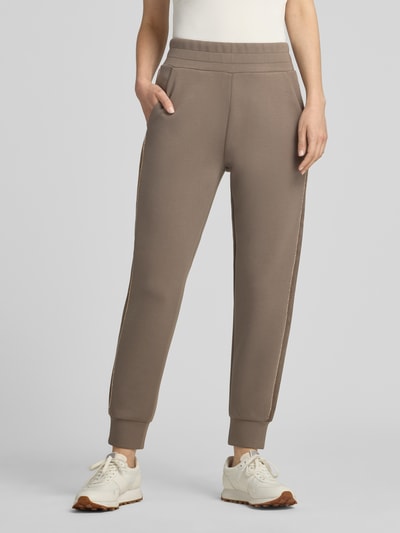 Frauenmodel trägt Slim Fit Sweatpants mit Viskose-Anteil Modell 'Victoire' von GUESS, elastischer Bund, Zierbesatz, Ganzkörperansicht von vorne.