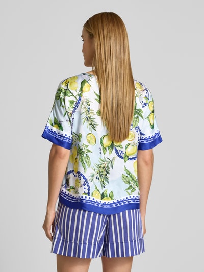 Vrouwenmodel draagt Relaxed Fit T-Shirt uit puur viscose met bloemen all-over print van Marc Cain, lichtblauw, geel en groen, ronde hals, half lange mouw, ruglengte 59 cm, mouwlengte 26 cm, detailopname rugaanzicht.