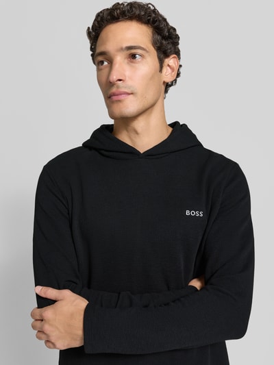 Männermodel trägt schwarzes Relaxed Fit Sweatshirt aus Baumwoll-Mix Modell 'Waffle LS' von BOSS, Nahaufnahme Oberkörper, Herren Hoodie von BOSS