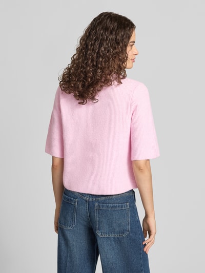 Frauenmodel trägt Boxy Fit Strickjacke aus Rippstrick Modell 'SILLY' von PIECES in Rosa-Melange, Material-Mix, Ganzkörperansicht Rückansicht.
