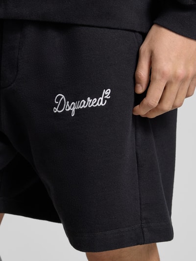 Männermodel trägt Sweatshorts aus reiner Baumwolle von Dsquared2 in Schwarz mit Label-Stitching und Taschen, Nahaufnahme Oberschenkel.