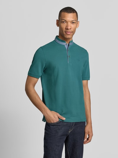 Männermodel trägt Regular Fit Poloshirt mit Stehkragen und Logo-Stitching von bugatti aus Reine Baumwolle, Ganzkörperansicht von vorne. Rückenlänge bei Größe M: 70 cm, Kurzarm, grüne Farbe, Label-Detail und kurze Knopfleiste.