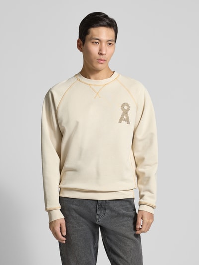 Männermodel trägt Relaxed Fit Sweatshirt aus Bio-Baumwoll-Mix Modell 'MEL' von Armedangels in Beige mit Logo-Stitching, Ganzkörperansicht von vorne.