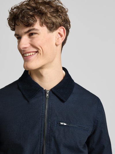 Männermodel trägt Jacke mit Brusttasche Modell 'FONTANA' von Blend in Dunkelblau, Reißverschluss, Umlegekragen, Nahaufnahme Oberkörper.