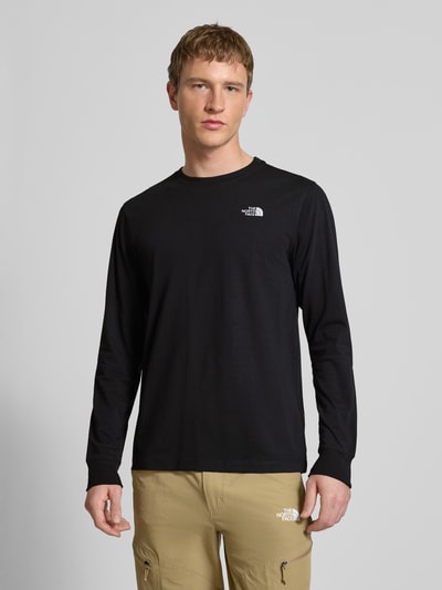 Męski model nosi Bluzka z długim rękawem z wyhaftowanym logo od The North Face, mieszanka bawełny, krój regular fit, okrągły dekolt, długość tyłu w rozmiarze M: 70 cm, kolor czarny, gładka tekstura, widok całej sylwetki z przodu