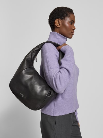 Frauenmodel trägt schwarze Hobo Bag mit Label-Detail Modell 'FARRAH' von LIEBESKIND BERLIN, texturiertes Leder, Seitenansicht, Nahaufnahme Oberkörper, Hauptfach mit Reißverschluss, Tragehenkel, Innenfach mit Reißverschluss, Größe: 40x26x20 cm, Schulterriemen 68 cm.