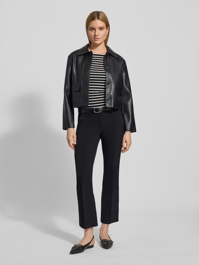 Frauenmodel trägt Flared Stoffhose in verkürzter Passform Modell 'FARAH' von Cambio, Material-Mix mit Stretch-Anteil, schwarze Farbe, französische Eingrifftaschen, Flared-Cut, verkürzte Passform, Bundweite 40 cm, Innenbeinlänge 74 cm, Ganzkörperansicht von vorne.
