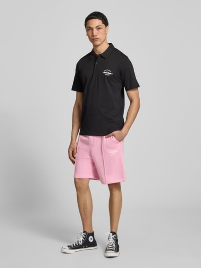 Männermodel trägt Sweatshorts mit Logo Modell 'KANE' von Jack & Jones aus Baumwoll-Mix in Rosa, Relaxed-Fit, Ganzkörperansicht von vorne.