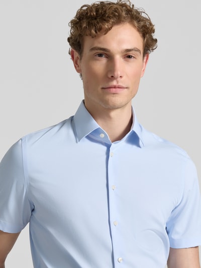 Männermodel trägt Slim Fit Business-Hemd mit Kentkragen von Jake*s in Hellblau, Elastischer-Material-Mix, Knopfleiste, Kurzärmelig, Nahaufnahme Oberkörper.
