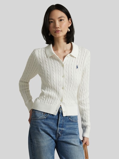 Modelka kobieca nosi Slim Fit Strickjacke aus reiner Baumwolle od Polo Ralph Lauren, biała, krój slim fit, długi rękaw, wzór warkoczowy, logo, jednolita, kołnierzyk koszulowy, dzianina, bawełna; widok całej sylwetki z przodu.