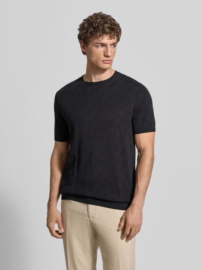 Männermodel trägt T-Shirt mit Viskose-Anteil und Rundhalsausschnitt Modell 'Ravao' von JOOP! Collection, Modern Fit, Baumwoll-Mix, Label-Detail, Rückenlänge 69 cm bei Größe M, einfarbig schwarz, feine Stricktextur, Ganzkörperansicht von vorne.