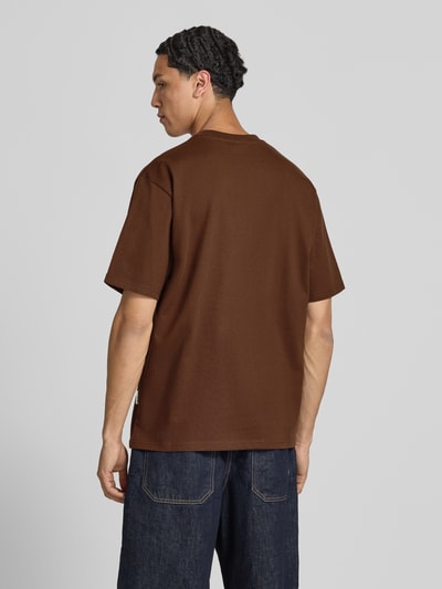 Männermodel trägt T-Shirt mit Statement-Print und Rundhalsausschnitt von Redefined Rebel in Braun aus Baumwoll-Mix, Relaxed-Fit, Rückansicht Ganzkörperansicht. Rückenlänge bei Größe M: 70 cm.