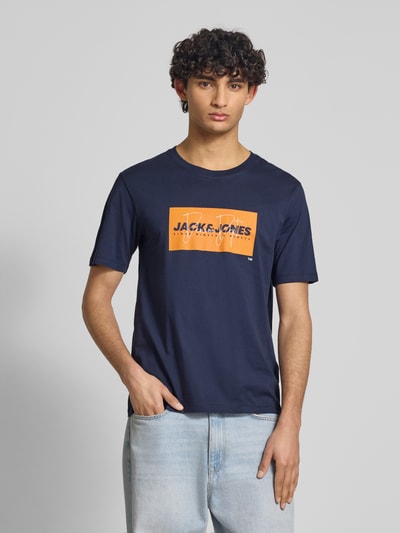 Männermodel trägt Regular Fit T-Shirt aus reiner Baumwolle Modell 'COLE' von Jack & Jones in Dunkelblau mit Label-Print, Ganzkörperansicht von vorne. Herren T-Shirt, Rundhalsausschnitt, Rückenlänge bei Größe M 70 cm.