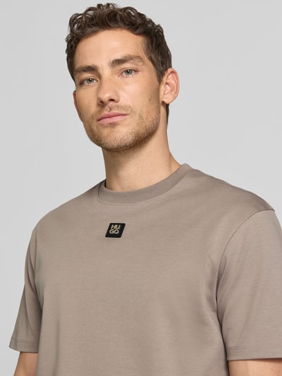 Männermodel trägt Regular Fit T-Shirt aus reiner Baumwolle Modell 'DALILE' von HUGO, Optik: Unifarben, Label-Patch, Nahaufnahme Oberkörper.