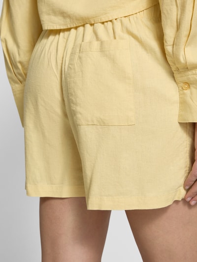 Frauenmodel trägt Shorts mit elastischem Bund Modell 'ALMIRA' von JJXX aus Viskose-Mix mit Leinen-Anteil in Gelb, Detailaufnahme Rückansicht. Damen Shorts Straight Fit, Bundweite 38 cm, Innenbeinlänge 10 cm.