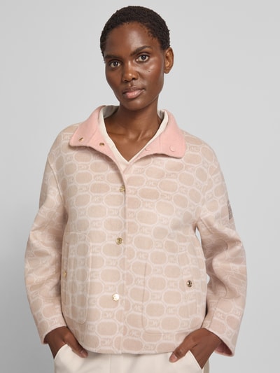 Frauenmodel trägt Jacke im Allover-Look mit Stehkragen von Marc Cain in Beige und Rosa aus Baumwoll-Mix, Nahaufnahme Oberkörper. Regular Fit, Knopfleiste, Eingrifftaschen, Rückenteil und Maße für Größe 36 berücksichtigt.