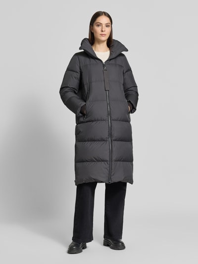 Frauenmodel trägt Regular Fit Daunenmantel mit abnehmbaren Rucksackriemen von Marc O'Polo, dunkler Farbton, glatte Oberfläche, Ganzkörperansicht von vorne. Damen Daunenmantel von Marc O'Polo.