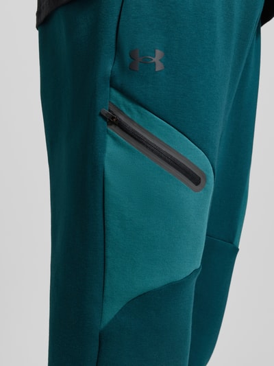 Männermodel trägt Regular Fit Sweatpants mit Logo-Print Modell 'Unstoppable' von Under Armour, Elastischer-Material-Mix, Nahaufnahme Oberschenkel.