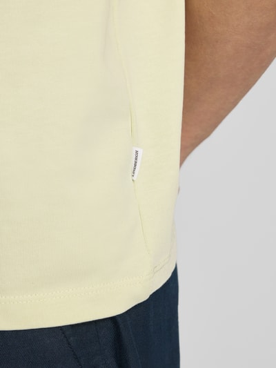 Männermodel trägt Oversized T-Shirt mit Rundhalsausschnitt von Lindbergh in Hellgelb, Reine Baumwolle, Label-Detail, Detailaufnahme.