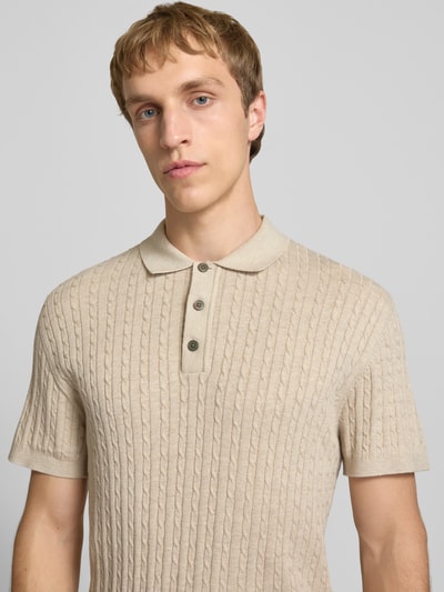 Männermodel trägt Slim Fit Strick-Poloshirt mit Zopfmuster Modell 'EMIL' von Jack & Jones im Baumwoll-Viskose-Mix, Knopfleiste, Nahaufnahme Oberkörper.