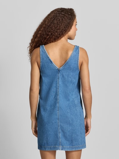 Frauenmodel trägt Ausgestelltes Jeanskleid aus reiner Baumwolle von Tommy Jeans in Denim-Optik, Mini-Länge, V-Ausschnitt, Twill, Ganzkörperansicht Rückansicht.