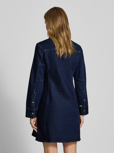 Vrouwenmodel draagt Regular Fit Minikleid in Denim-Optik Modell Classic van Calvin Klein Jeans, donkerblauw, sportmanchetten, lange mouwen, hemdblousekraag, knoopsluiting, elastische katoenmix, ruglengte 89 cm, borstwijdte 44 cm, mouwlengte 63 cm, volledig zicht van achteren.