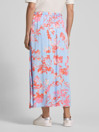 Frauenmodel trägt Midirock aus Viskose Modell 'Aveline' von mbyM, hellblau mit korallrotem Allover-Blumenmuster, A-Linie, elastischer Bund, Ganzkörperansicht Rückansicht.