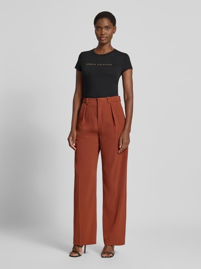 Kobieta modelka nosi Damski t-shirt 'Slim Fit T-Shirt aus reiner Baumwolle' od Armani Exchange, czarny, krój slim fit, detal z logo, okrągły dekolt, bawełna, długość tyłu w rozmiarze S: 59 cm, widok całej sylwetki z przodu.