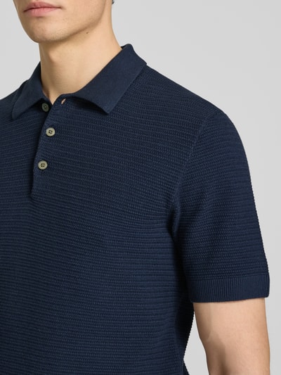 Männermodel trägt Regular Fit Poloshirt mit Strukturmuster Modell 'Riley' von Jack & Jones Premium in Dunkelblau, Nahaufnahme Oberkörper.
