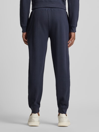 Männermodel trägt Comfort Fit Sweatpants aus Baumwoll-Mix Modell 'STRUCTURE PANTS' von BOSS, Optik: Unifarben, Struktur, Ganzkörperansicht Rückansicht.