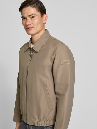 Mannenmodel draagt Regular Fit blouson met elastische rompzoom van Marc O'Polo, look: effen, platte kraag, ritssluiting, labelpatch, lange mouw, drukknoop, steekzakken, binnenzak, regular fit pasvorm, zijaanzicht bovenlichaam.