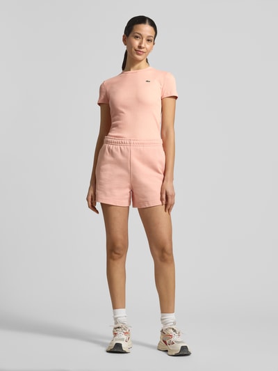 Vrouwenmodel draagt Slim Fit T-shirt uit puur katoen van Lacoste Sport in effen kleuren met logostitching, ronde hals, ribstructuur, korte mouw. Ganzichaansicht van voren.